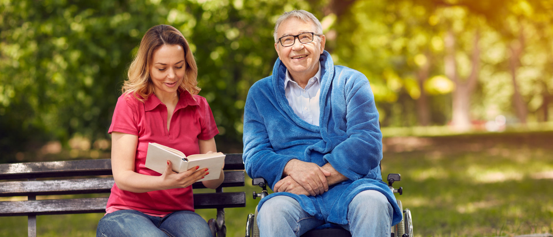 adult woman reading a book to a senior man