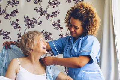 caregiver assisting senior woman to dress up