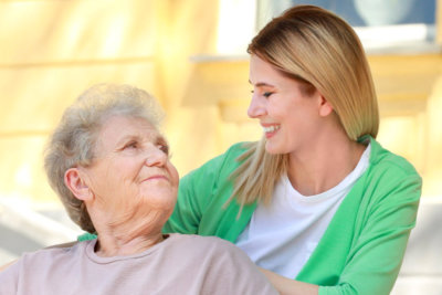 female caregiver and senior woman looking at each other outdoor