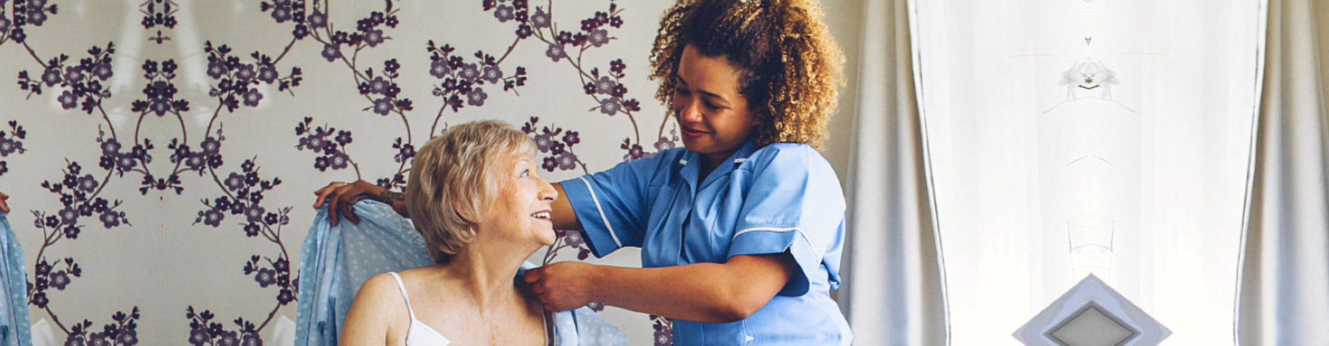 caregiver assisting senior woman to dress up