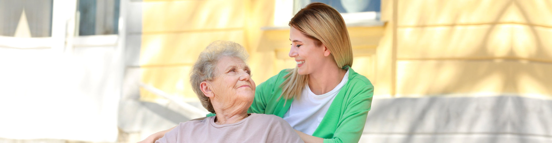 female caregiver and senior woman looking at each other outdoor